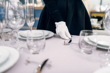 Waitress in gloves puts the knife, table setting
