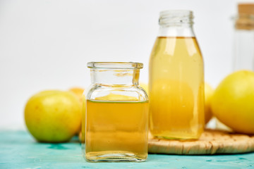 Glass Bottle of apple organic vinegar on blue background.