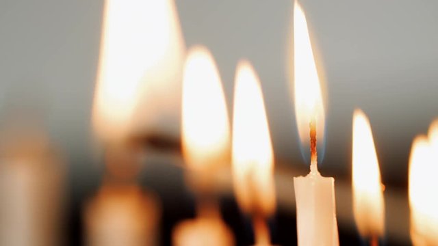 Detail shot of a group of white candles being lit for the Jewish holiday of Hanukkah, selective focus