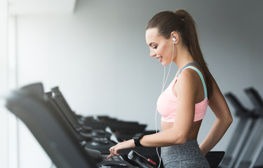 Fototapeta na wymiar Woman adjusting speed on treadmill, doing cardio workout
