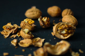 Crushed and whole walnuts close up, selective focus, black background