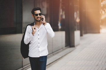 Young executive businessman using a mobile phone in the business district with skyscrapers buildings background