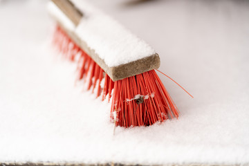 Besen mit roten Borsten im Schnee im Schnee