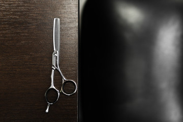 Fototapeta na wymiar scissors for highlighting on a dark wooden table. Hairdressing Workspace. Work place for hairdresser. Professional Salon Supplies. Hair. Place for text. copy space