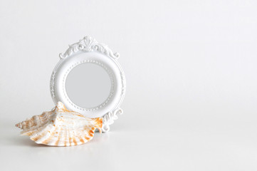White round vintage photo frame with light grey color inside and a big sea shell, empty space for your text on the left, on white background. Clipping path inside the frame