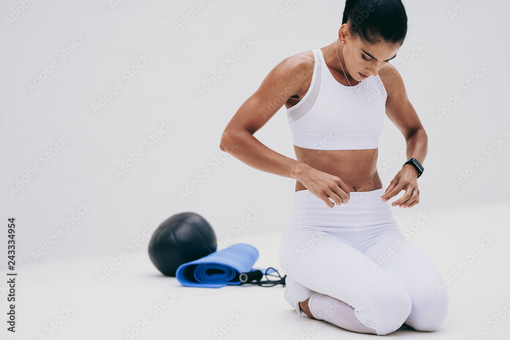 Wall mural fitness woman sitting on floor with her fitness equipment