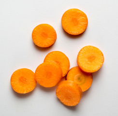 rounded slices of carrot on white, with shadow, view from above
