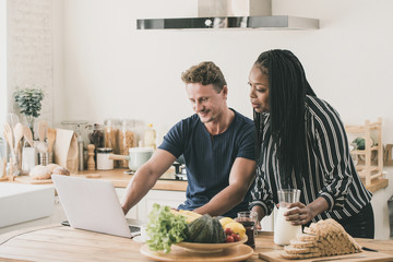 Multi-ethnic couple having a breakfast while working at home