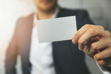 man hand showing blank white business card in front