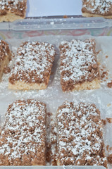 Top view, close distance of four freshly baked, homemade, crumb cake rectangles on parchment paper on display and for sale at a tropical farmers market