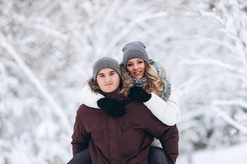 Fototapeta na wymiar Embracing couple looking at camera with smiles in winter park