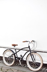 Fototapeta na wymiar Vintage cruiser bicycle near white wall