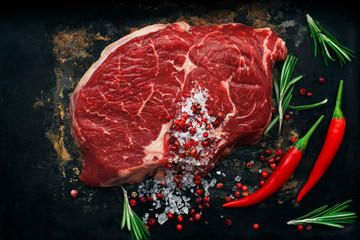 Rib eye steak with spices on the black background.