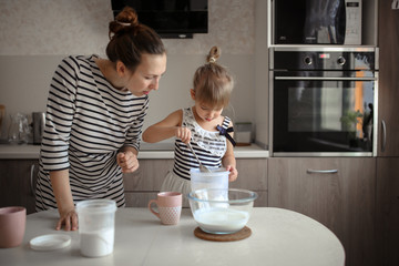 mother and daughter make dough for pancakes