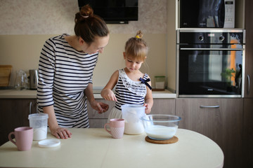 Obraz na płótnie Canvas Funny daughter and mother cook together in kitchen