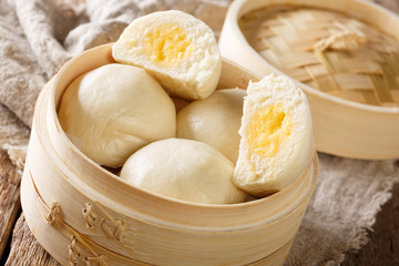 Steamed Chinese bun with custard cream stuff filling in bamboo wooden container. horizontal