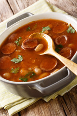 Polish cuisine Breton beans with sausage close-up in a pan. vertical