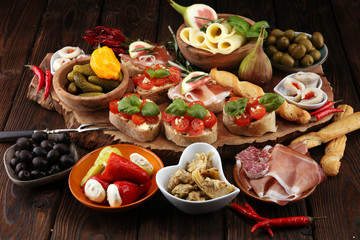 Fototapeta na wymiar Italian antipasti wine snacks set. Cheese variety, Mediterranean olives, pickles, Prosciutto di Parma, tomatoes, artichokes
