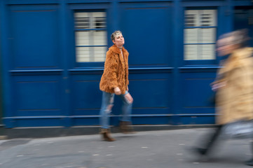 Young woman walking on the street in front of blue wall