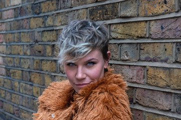 Portrait of a young woman against a brick wall