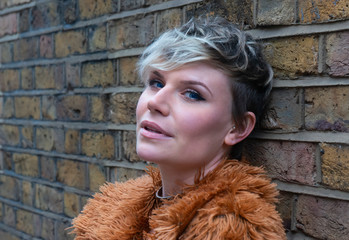 Portrait of a young woman leaning against a brick wall