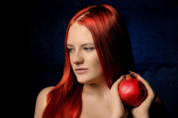 portrait of beautiful girl with red hair and pomegranate fruit on the background of blue wall. different poses.