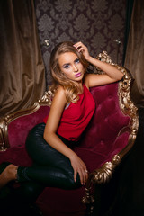 Beautiful girl in a red shirt posing in a classic red chair
