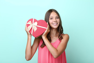 Cute girl holding gift box on mint background