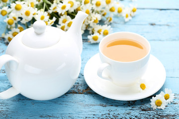Cup of tea with chamomile flowers on blue wooden table