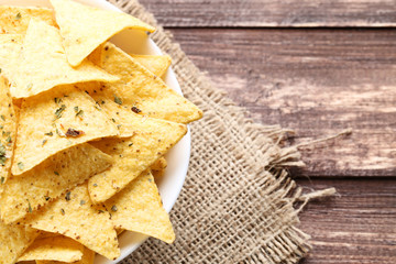 Potato chips in bowl with sackcloth on wooden table