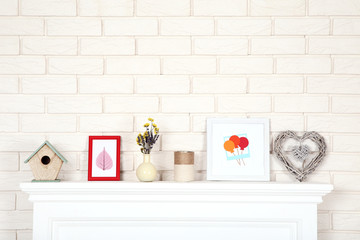 White fireplace with photo frames, nesting box and flowers in vase