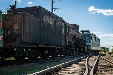 Fototapeta na wymiar Old steam locomotive beside a railway station platform. Retro train.