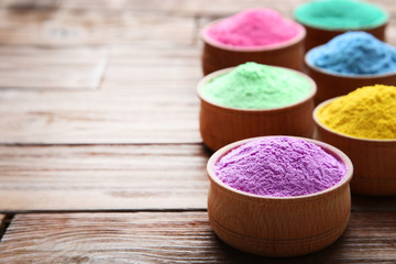Obraz na płótnie Canvas Colorful holi powder in bowls on brown wooden table