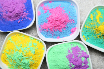Colorful holi powder in bowls on grey background