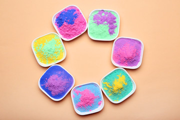 Colorful holi powder in bowls on beige background