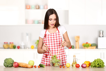 Obraz na płótnie Canvas Beautiful woman cooking salad in the kitchen