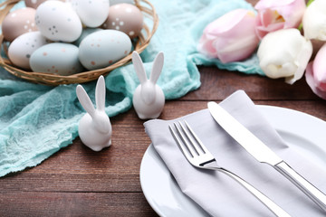 Kitchen cutlery with easter eggs and ceramic rabbits on wooden table