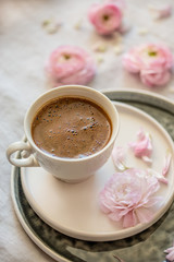 Spring concept. A cup of black coffee and pink ranunculus
