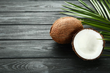 Ripe coconuts with palm leafs on black wooden table