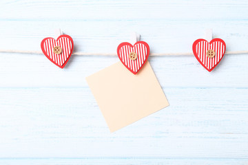 Blank paper hanging on rope with red hearts