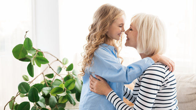 Happy grandma and granddaughter touching noses at home