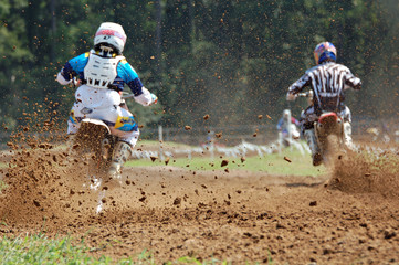Two motocross riders, back view, kicking up dirt