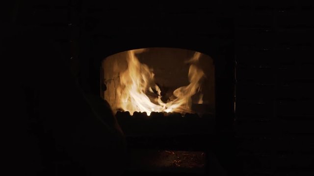 Man opens the door of a burning fire brick stove