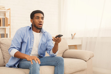 African-american man watching tv at home, copy space