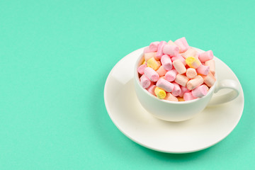 Cup with marshmallow on a green background. Copy space.