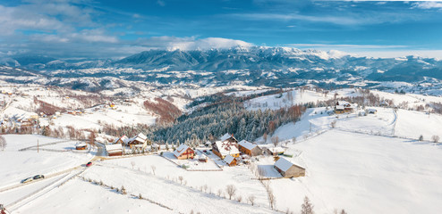 Fototapeta na wymiar Winter in Romania panoramic view of the Carpathian Mountains and the traditional village Pestera on the Rucar-Bran Pass