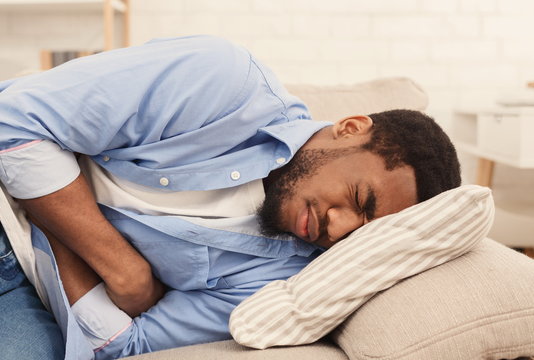 Black man suffering from stomach ache at home