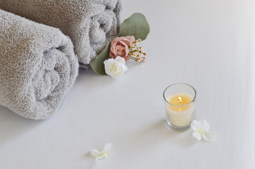 Beauty products with towels, flowers and candle.