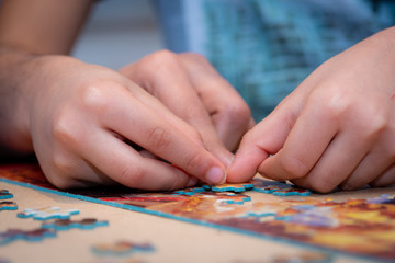 Fototapeta na wymiar Adult and child solving a jigsaw puzzle on a table. 