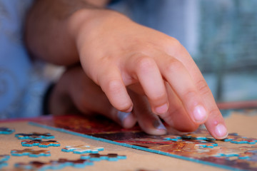 Obraz premium Adult and child solving a jigsaw puzzle on a table. 